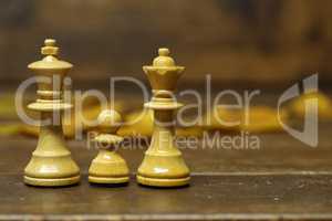 Family - White Queen, King and Pawn - Chess Pieces on a Blurry Brown Background