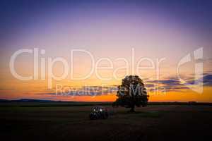 tractor with lights on at sunset