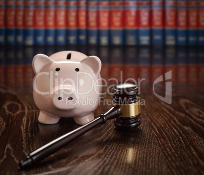 Gavel and Piggy Bank on Wooden Table With Law Books In Backgroun