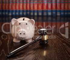 Gavel and Piggy Bank on Wooden Table With Law Books In Backgroun