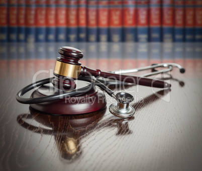 Gavel and Stethoscope on Wooden Table With Law Books In Backgrou