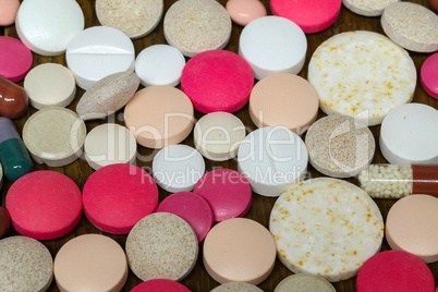 Various pills and capsules lie on the table