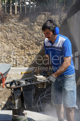 Construction worker compacting soil using compactor. Work with tamping machine