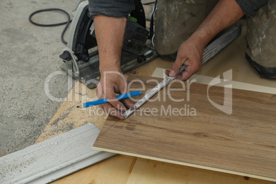 Worker measures and saws off fragments of steps for stairs