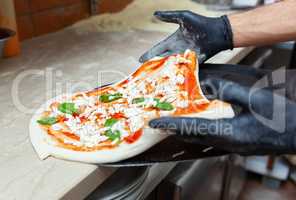 Raw margherita pizza on baking shovel.