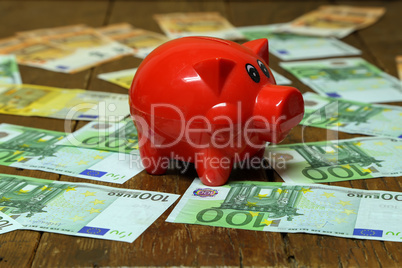 Red piggy bank stands on euro of different euro notes