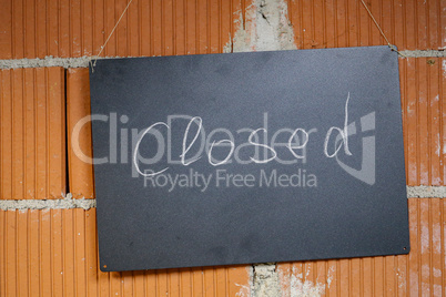 Closed - A Nameplate hanging on a brick wall