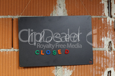 Closed - A Nameplate hanging on a brick wall