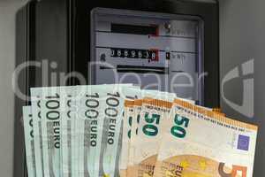 Old electricity meter and euro banknotes close up