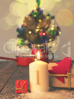 First Advent candle burning with gift boxes, vintage tone styliz