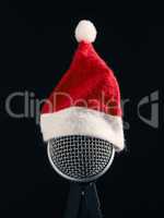 Close up of a microphone with the hat of Santa on a dark studio