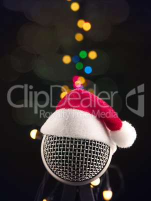 Close up of a microphone with the hat of Santa on a dark studio