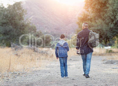 Mixed Race Father And Son Outdoors Walking With Fishing Poles