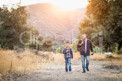 Mixed Race Father And Son Outdoors Walking With Fishing Poles