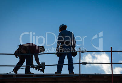 Construction Workers Silhouette on Roof of Building.
