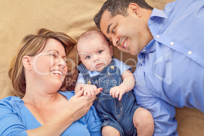 Young Mixed Race Couple Laying With Their Infant On A Blanket