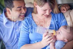 Happy Attractive Mixed Race Couple Bottle Feeding Their Son.