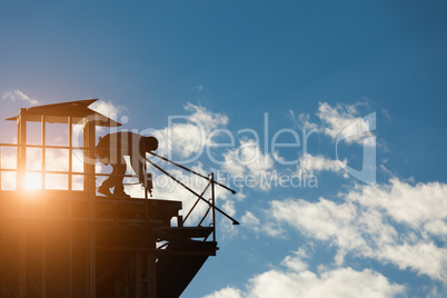 Construction Workers Silhouette on Roof of Building