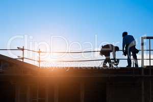Construction Workers Silhouette on Roof of Building