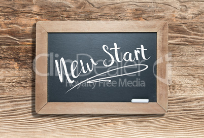 New Start Written on Slate Chalk Board Against Aged Wood Backgro