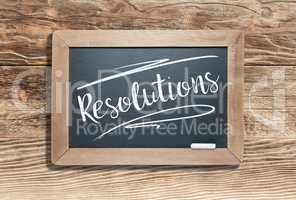 Resolutions Written on Slate Chalk Board Against Aged Wood Backg