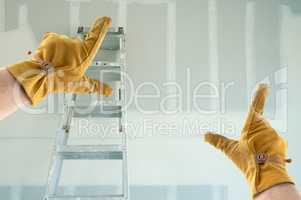 Contractor Hands In Leather Gloves Framing New Blank Drywall