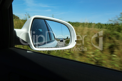 View of the road in the side mirror of the car
