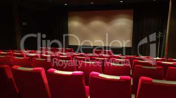 Empty cinema hall, cinema screen and row of red sits
