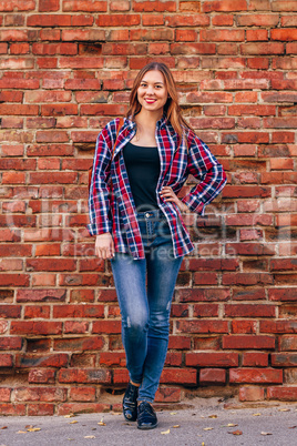 Portrait of young woman standing against brick wall