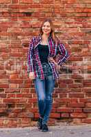 Portrait of young woman standing against brick wall