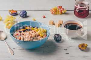 Porridge with fresh plum, green grapes and cup of coffee.