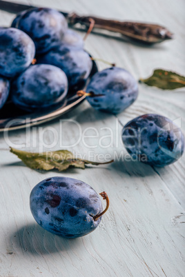 Plums on wooden surface with leaves