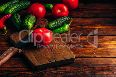 Cucumbers, tomatoes and chili peppers over wooden background.