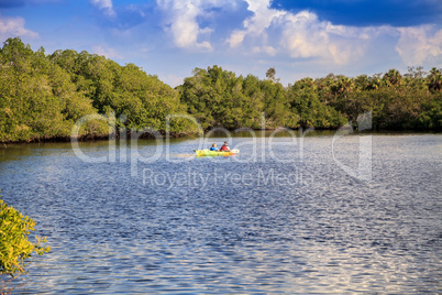 Kayakers paddle a colorful kayak under a blue sky