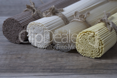 Different sorts of dry pasta on wooden background.