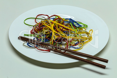 Elastic multi-colored rubber bands lie in a plate like spaghetti