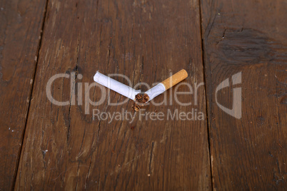 Broken filter cigarette lies on a wooden table