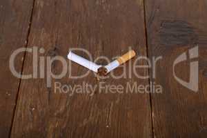 Broken filter cigarette lies on a wooden table
