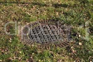 A metal sewer hatch in the grass