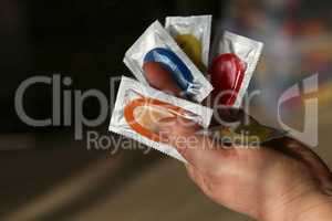 a large number of colorful condoms in a man's hand