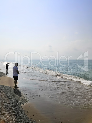 Fishermen catch fish with fishing rods in the sea.