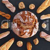 Different types of bread and rolls in the top view. Kitchen or bakery poster design on dark.