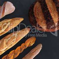 Different types of bread and rolls in the top view. Kitchen or bakery poster design on dark.