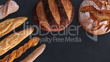Different types of bread and rolls in the top view. Kitchen or bakery poster design on dark.