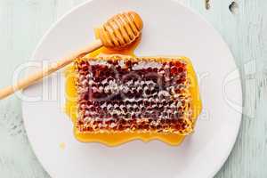 Honeycomb on white plate with honey dipper