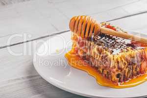 Honeycomb on plate with honey dipper