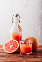 Bottle of grapefruit juice with glass and fruit