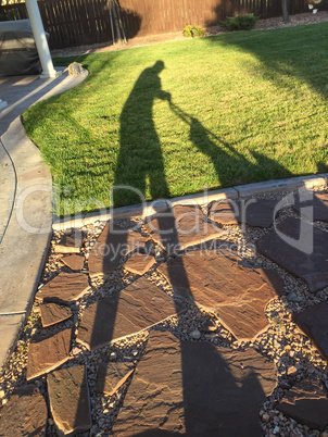 Shadow of Man Pushing Lawn Mower Over Grass