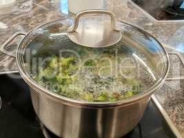 Broccoli soup is cooked on a stove, brought to a boil