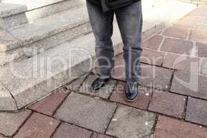Legs in jeans and black shoes at the granite steps